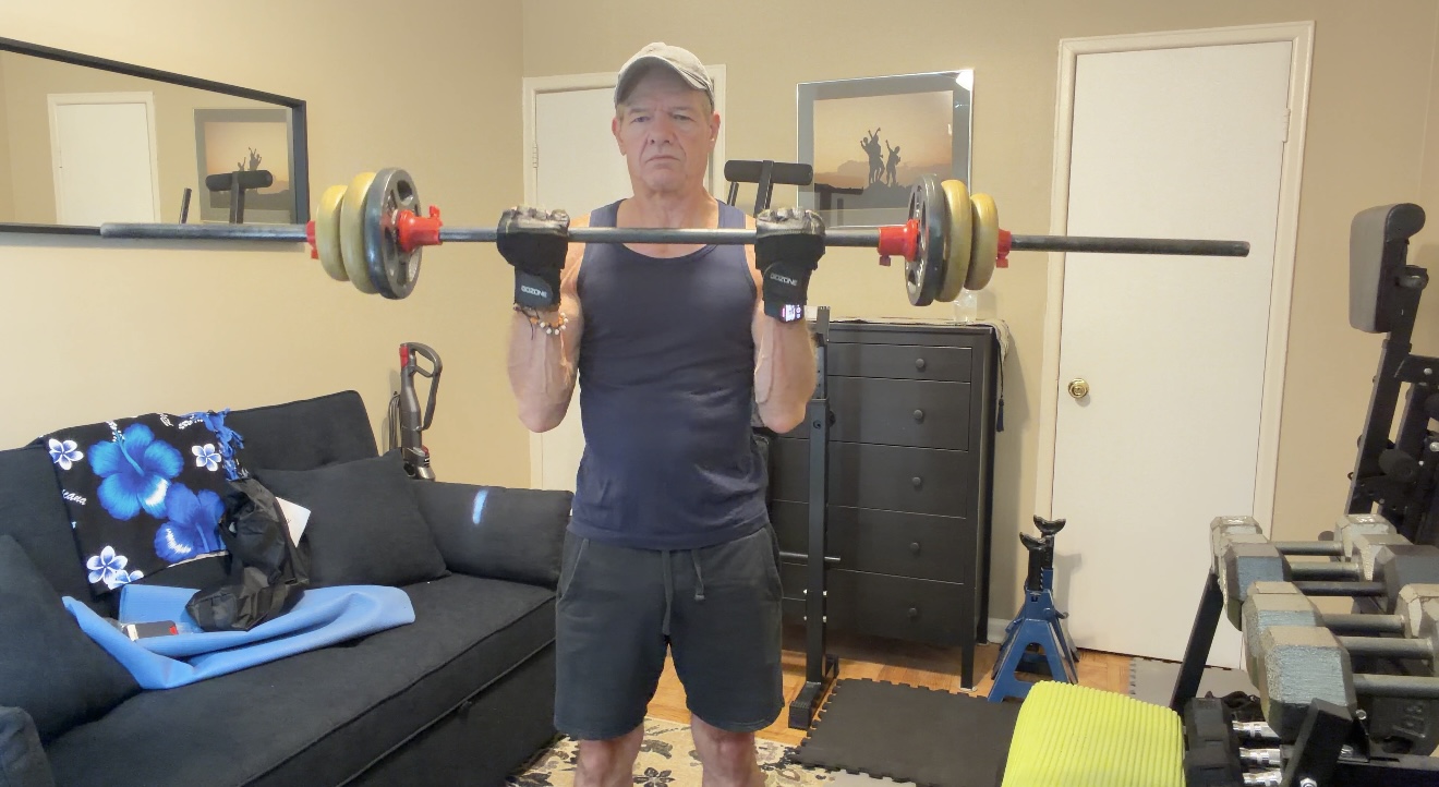 John demonstrating the controlled top position of a standing barbell biceps curl