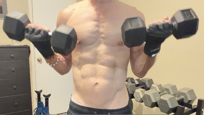 John demonstrating the controlled top position of a standing dumbbell biceps curl