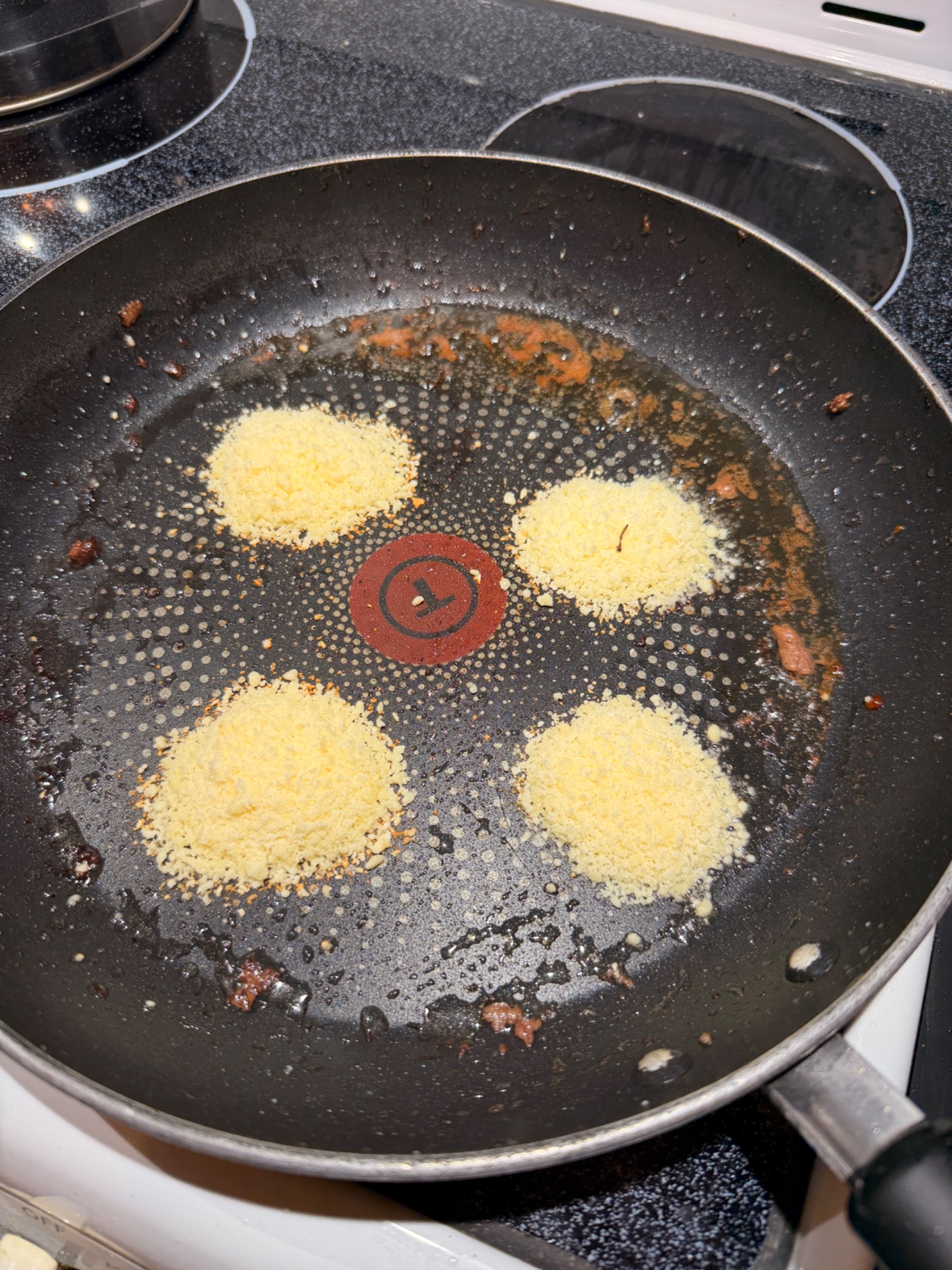 Four small piles of grated Parmesan in a frying pan