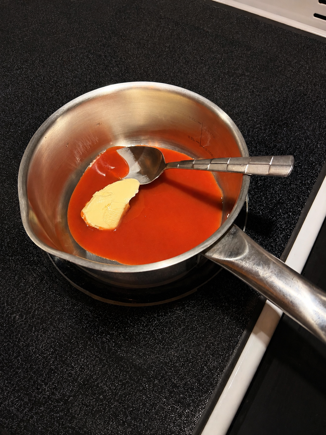 Hot sauce and butter being combined in a saucepan