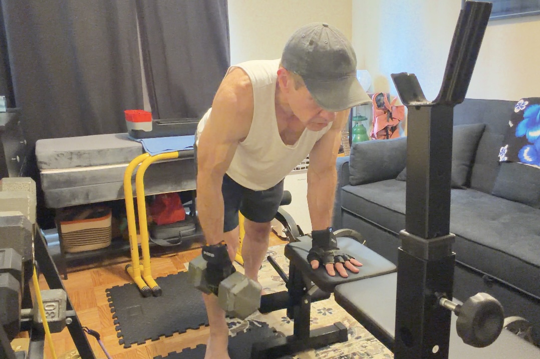 John demonstrating the supported starting position of a one-arm dumbbell row