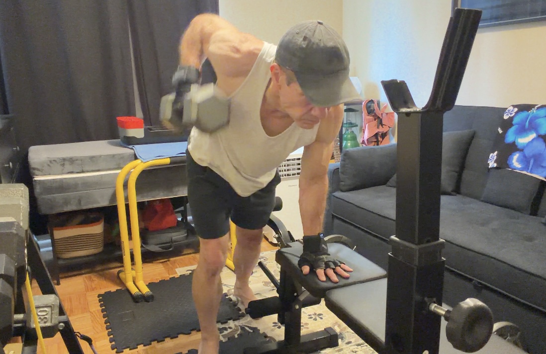 John demonstrating the top position of a one-arm dumbbell row with his elbow drawn toward his hip