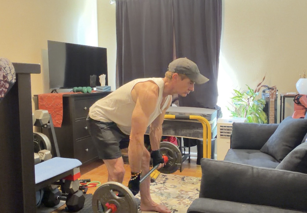 John demonstrating the controlled hip-hinge position of a Romanian deadlift with the bar close to his legs