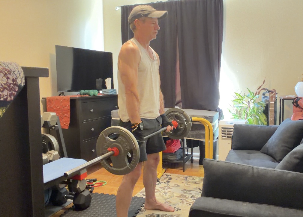 John standing tall with the bar close to his thighs at the start of a Romanian deadlift